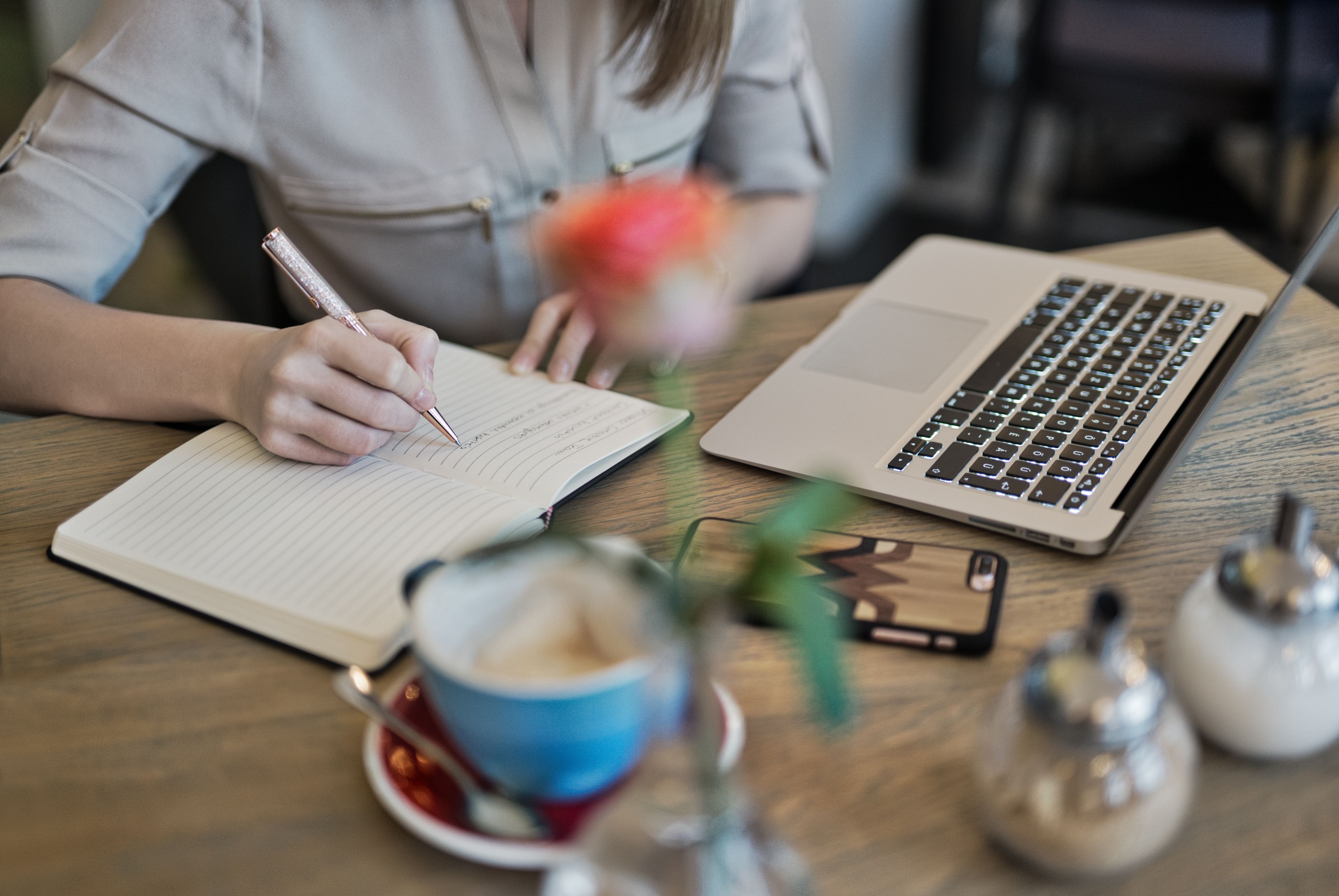Writer taking notes beside a laptop and coffee, drafting everyday content with an AI writing assistant